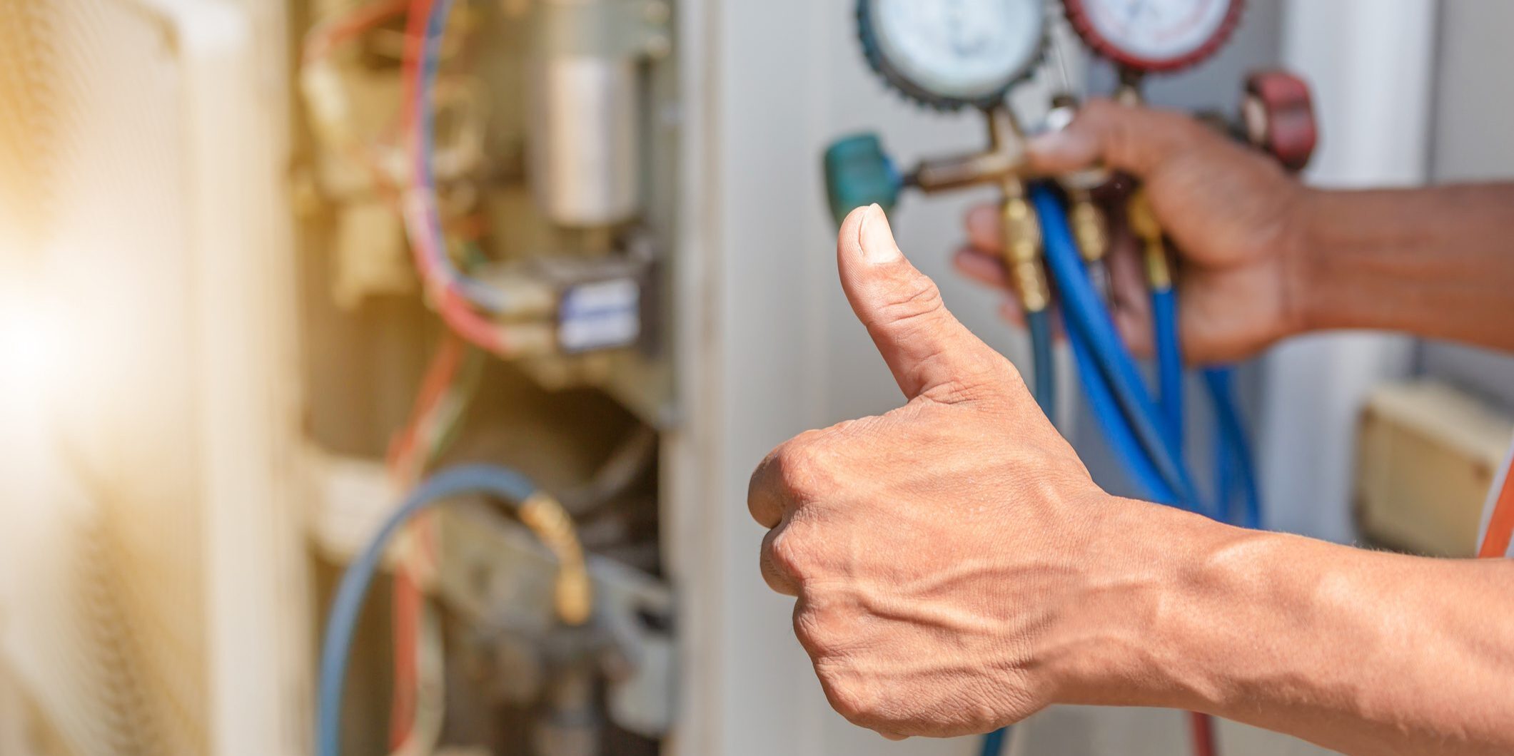 Technician giving thumbs up near HVAC gauges