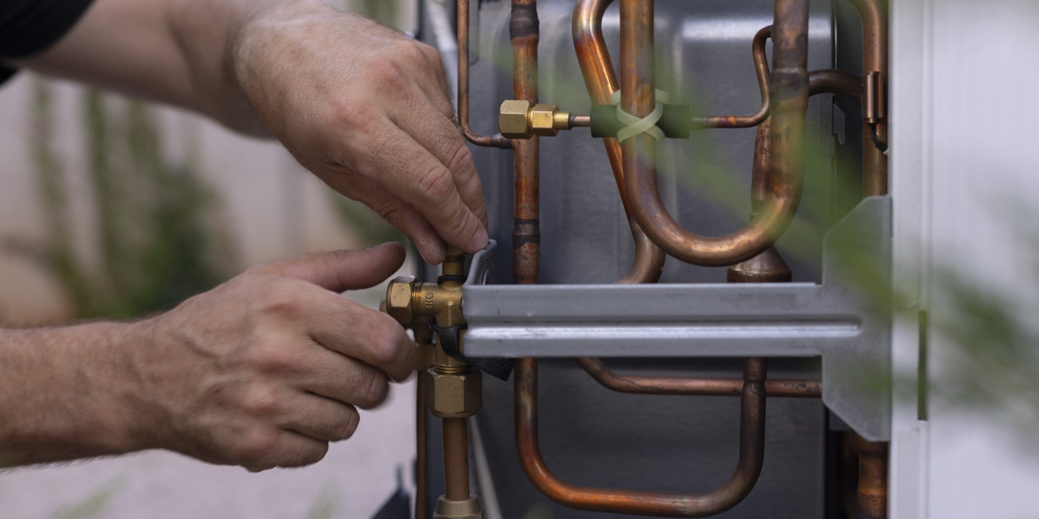 Technician adjusting copper HVAC unit pipes