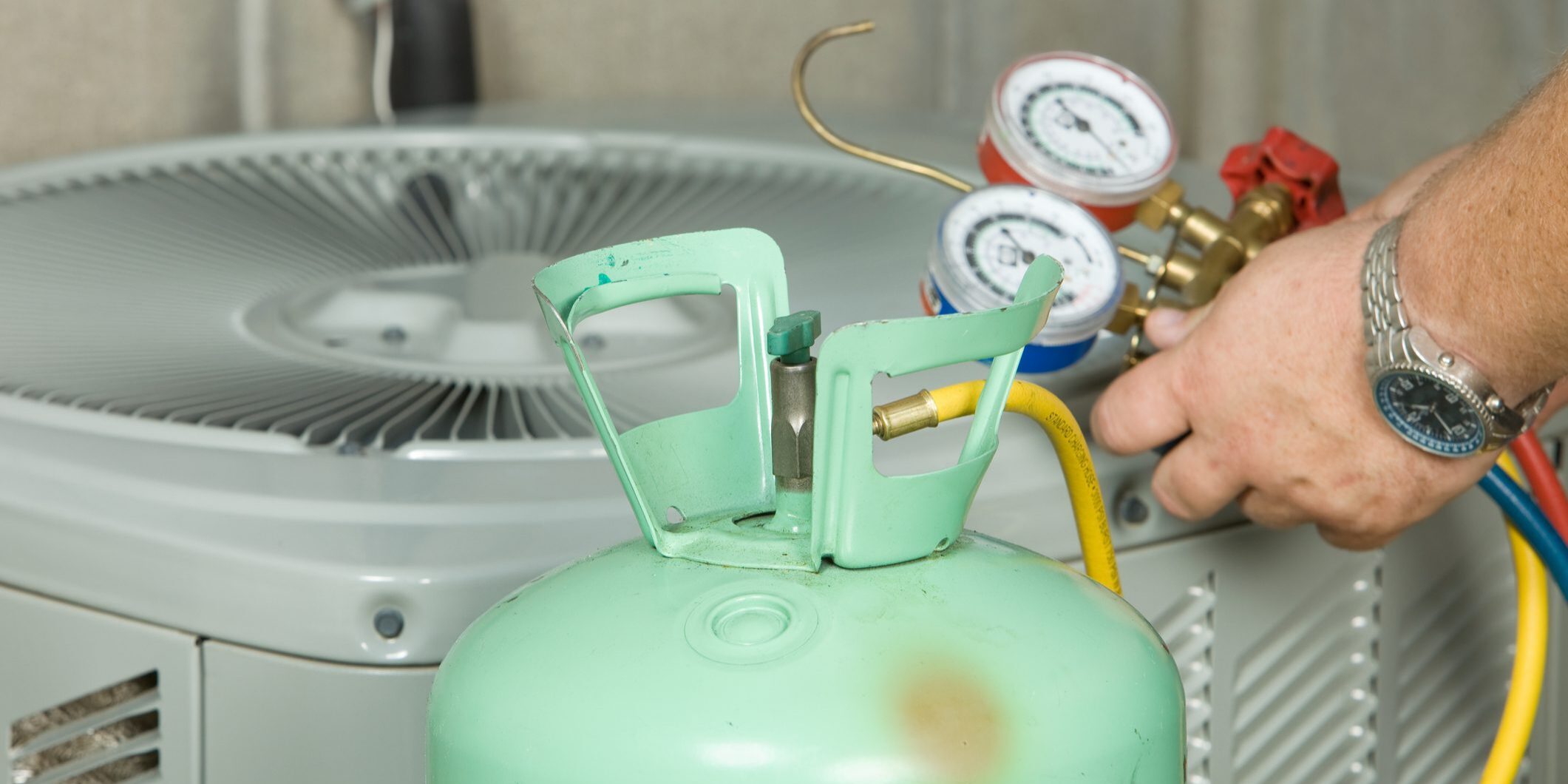 Technician connecting refrigerant tank to air conditioner