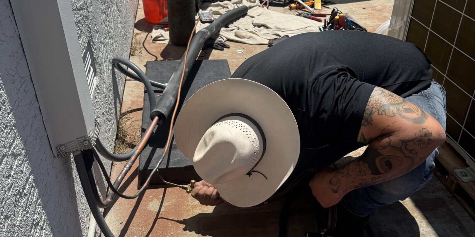 HVAC technician kneeling installing outdoor air conditioner