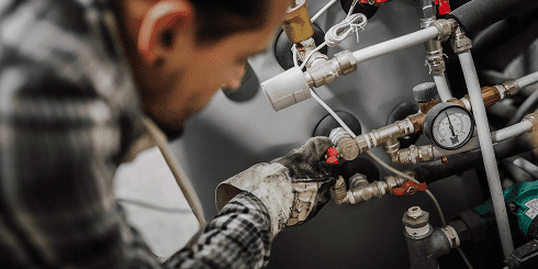Technician adjusting industrial machinery pipes
